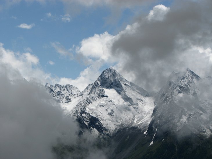 Super Blick durch die Wolken auf verschneite Bergspitzen